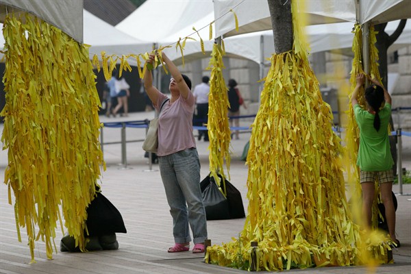 A mother and her daughter tie yellow ribbons with messages for missing passengers and victims aboard the sunken ferry Sewol at a group memorial altar in Seoul, South Korea, July 28, 2014 (AP photo by Lee Jin-man).