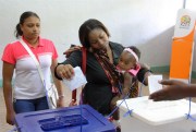 A woman holding her baby casts her vote, during municipal elections held in the city of Maputo, Mozambique, Nov. 20, 2013 (AP photo by Ferhat Momade).