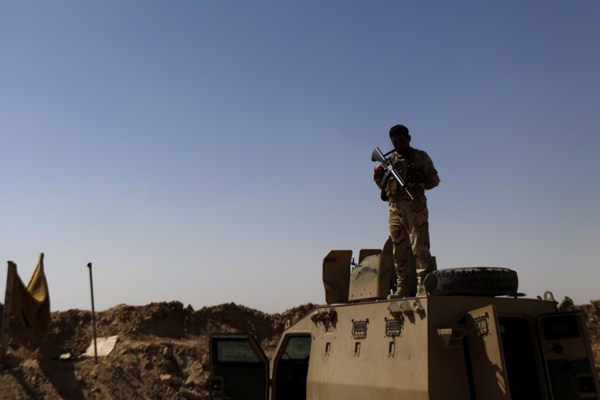 A Kurdish Peshmerga fighter stands guard atop an armored vehicle at a combat outpost on the outskirts of Makhmour, Sept. 6, 2014 (AP photo by Marko Drobnjakovic).