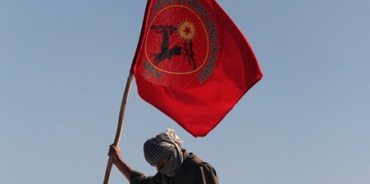 A masked man in a guerrilla outfit holds a flag of the rebel Kurdistan Worker Party (PKK), Diyarbakir, Turkey, March 21, 2014 (AP photo).