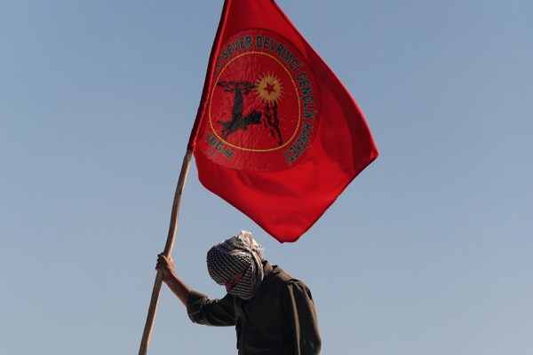 A masked man in a guerrilla outfit holds a flag of the rebel Kurdistan Worker Party (PKK), Diyarbakir, Turkey, March 21, 2014 (AP photo).