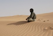 A man sits alone near the road between the Dakhla Refugee Camp and Awsaard Refugee Camp, June 24, 2003 (UN photo by Evan Schneider).