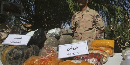 An Iranian police officer stands behind drugs which were seized on the border with Afghanistan, June 1, 2014 (AP photo by Vahid Salemi).