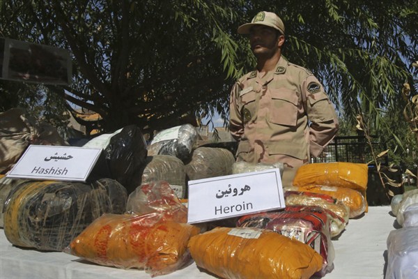 An Iranian police officer stands behind drugs which were seized on the border with Afghanistan, June 1, 2014 (AP photo by Vahid Salemi).