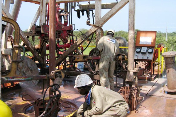 Chadian workers guide a pipe down a well in the Doba oil fields in southern Chad, Oct. 10, 2003 (AP photo by Susan Linnee).
