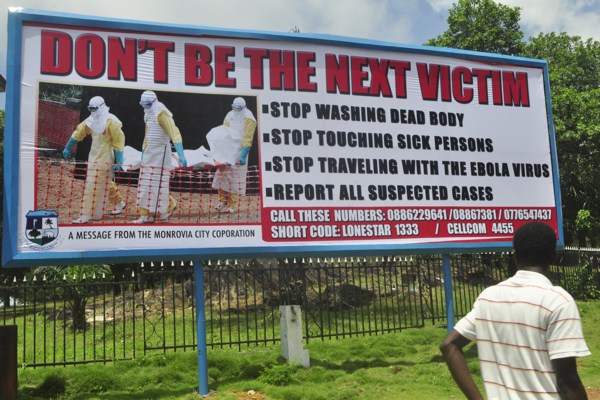 A man walks past a billboard warning people of the deadly Ebola virus in Monrovia, Liberia, Oct. 10, 2014 (AP photo by Abbas Dulleh).