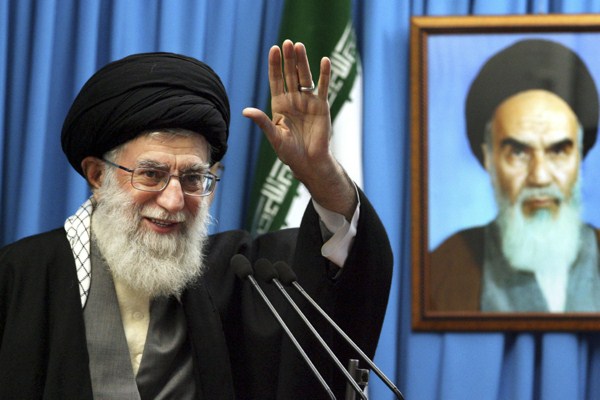 Iranian supreme leader Ayatollah Ali Khamenei waves to the worshippers, in front of a portrait of the late revolutionary founder Ayatollah Khomeini at the Tehran University campus, Iran, Feb. 3, 2012 (AP photo/Office of the Supreme Leader).