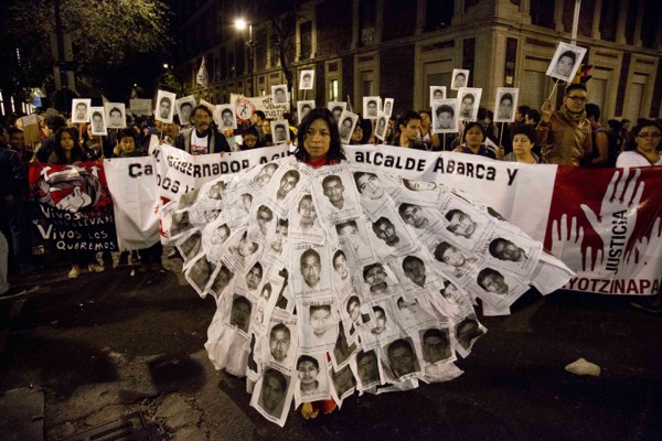 A woman marches with leaflets with the images of missing students attached to her body, during a protest against the disappearance of 43 students from the Isidro Burgos rural teachers college, in Mexico City, Oct. 22, 2014 (AP photo by Eduardo Verdugo).