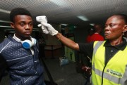 Health officials use a thermometer to screen passengers at the arrival hall of Murtala Mohammed International airport in Lagos, Nigeria, Oct. 20, 2014 (AP photo by Sunday Alamba).