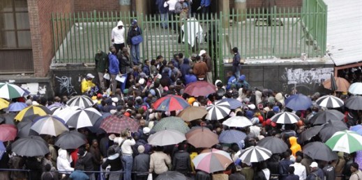 Zimbabweans queue in the rain outside immigration offices in Johannesburg as they wait to apply to become legal immigrants, Dec. 15, 2010 (AP photo by Denis Farrell).