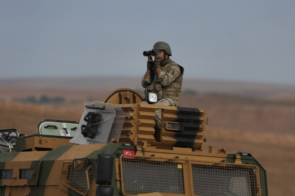 A Turkish forces soldier on an armored vehicle uses his binoculars as he patrols on the outskirts of Suruc, at the Turkey-Syria border, overlooking Kobani, Syria, Oct. 16, 2014 (AP photo by Lefteris Pitarakis).