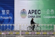 A man rides a bicycle past a billboard of APEC China 2014 with its slogans near the venues for the Asia-Pacific Economic Cooperation summit in Beijing, China, Nov. 7, 2014. (AP photo by Andy Wong).