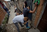 A police officer searches a man during a drug raid at the “21” slum in Buenos Aires, Argentina, April 2014 (AP photo by Natacha Pisarenko).