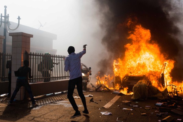 A car burns outside the parliament building in Burkina Faso as people protest against their longtime President Blaise Compaore, who seeks another term in Ouagadougou, Burkina Faso, Oct. 30, 2014 (AP photo by Theo Rena).
