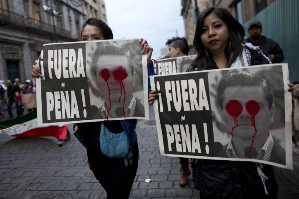 Protesters hold up posters that read in Spanish “Pena Out!” during a march to pressure the government into finding 43 missing college students, Mexico City, Nov. 20, 2014 (AP photo by Rebecca Blackwell).