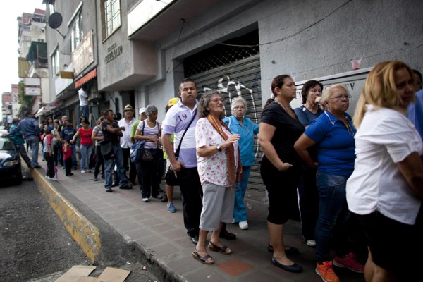 People wait in line to enter a small market to try to buy items like disposable diapers, laundry detergent and razors in downtown Caracas, Venezuela, Oct. 23, 2014 (AP photo by Ariana Cubillos).