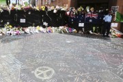 Police stand watch over flower tributes and messages written on the footpath outside the Lindt cafe in the central business district of Sydney, Australia, Dec. 17, 2014 (AP photo by Rob Griffith).