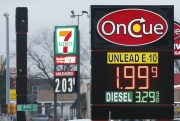 Gasoline is advertised for $1.99 per gallon at an On Cue station and $2.03 per gallon at the nearby 7-11 in south Oklahoma City, Dec. 5, 2014 (AP photo by Sue Ogrocki).