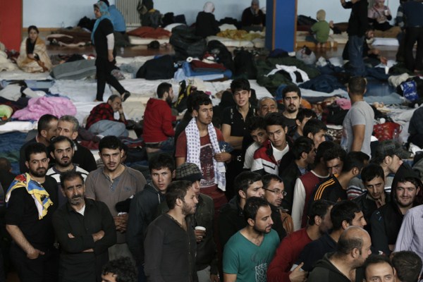 Dozens of immigrants who arrived on a cargo ship from Turkey line up for meals in a basketball arena where they have been given temporary shelter, Ierapetra, Crete, Nov. 28, 2014 (AP photo by Petros Giannakouris).