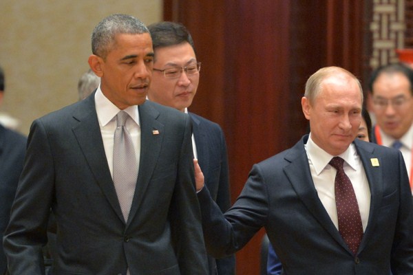 Russian President Vladimir Putin passes by U.S. President Barack Obama at the Asia-Pacific Economic Cooperation (APEC) Summit, Beijing, China, Nov. 11, 2014 (AP Photo/RIA Novosti).