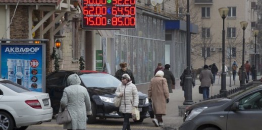People walk past a display with currency exchange rates in central Moscow, Dec. 1, 2014 (AP photo by Alexander Zemlianichenko).