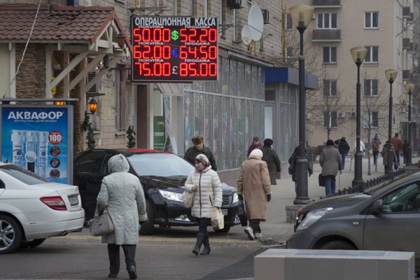 People walk past a display with currency exchange rates in central Moscow, Dec. 1, 2014 (AP photo by Alexander Zemlianichenko).