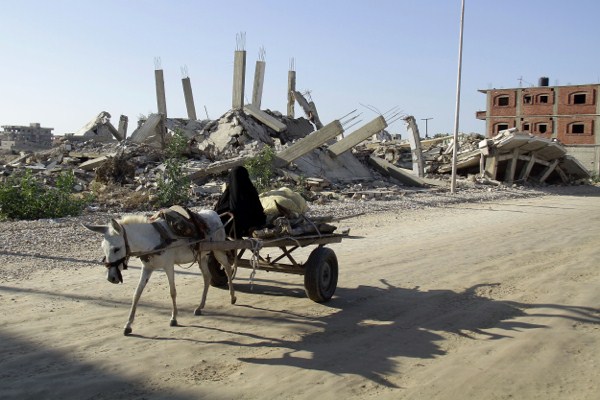 A woman maneuvers a donkey cart on a street amid debris of buildings demolished by the Egyptian army on the Egyptian side of border town of Rafah, Nov. 6, 2014 (AP Photo/El Shorouk newspaper, Ahmed Abd El-Latif).