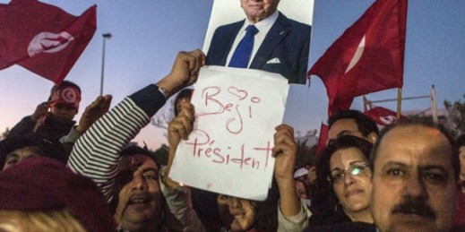 Supporters of Beji Caid Essebsi hold his portrait outside his party headquarters after he was elected Tunisian President, Dec. 22, 2014 in Tunis, Tunisia (AP photo by Ilyess Osmane).