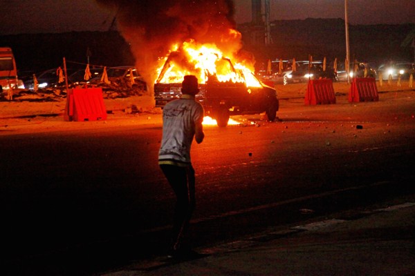 An Egyptian looks at a vehicle lit on fire during a riot outside the Air Defense Stadium in a suburb east of Cairo, Egypt, Feb. 8, 2015 (AP photo by Ahmed Abd El-Gwad, El Shorouk Newspaper).