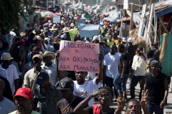 A demonstrator holds a sign that reads in Creole “Coalition MOLEGHAF says: Down Martelly, down MINUSTAH” during a protest in Port-au-Prince, Haiti, Feb. 4, 2015 (AP photo by Dieu Nalio Chery).
