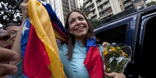 Former Congresswoman and opposition leader Maria Corina Machado holds up the Venezuelan flag outside of the Attorney General Office in Caracas, Venezuela, Dec. 3, 2014 (AP photo by Ariana Cubillos).