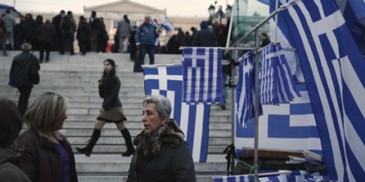 Women talk next to Greek flags for sale in Syntagma square, Feb. 16, 2015 (AP photo by Petros Giannakouris).