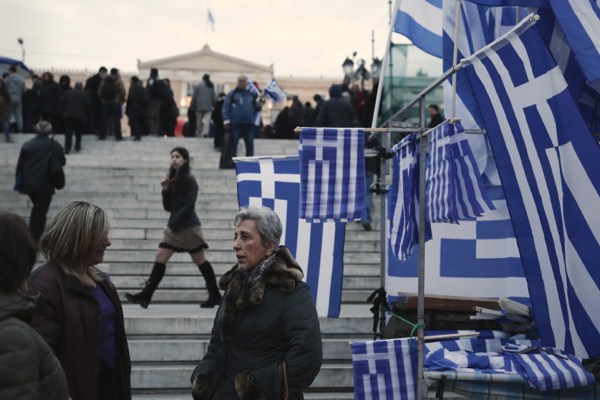 Women talk next to Greek flags for sale in Syntagma square, Feb. 16, 2015 (AP photo by Petros Giannakouris).