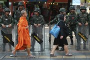 A Buddhist monk and a woman walk past a line of Thai soldiers guarding the Victory Monument to prevent anti-coup demonstrations, Bangkok, Thailand, May 30, 2014 (AP photo by Wason Wanichakorn).