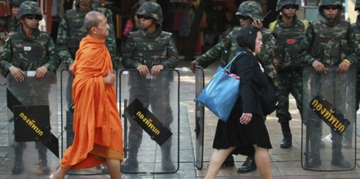 A Buddhist monk and a woman walk past a line of Thai soldiers guarding the Victory Monument to prevent anti-coup demonstrations, Bangkok, Thailand, May 30, 2014 (AP photo by Wason Wanichakorn).
