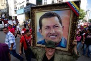 A man holds a framed image of the late President Hugo Chavez during a pro-government rally ahead of the two-year anniversary of his death, Caracas, Venezuela, Feb. 28, 2015 (AP photo by Fernando Llano).