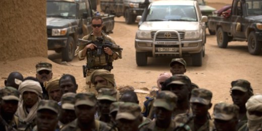 A French soldier stands watch behind Malian soldiers during a visit by the head of France's Operation Serval and Mali’s army chief of staff to a Malian army base, Kidal, Mali, July 27, 2013 (AP photo by Rebecca Blackwell).