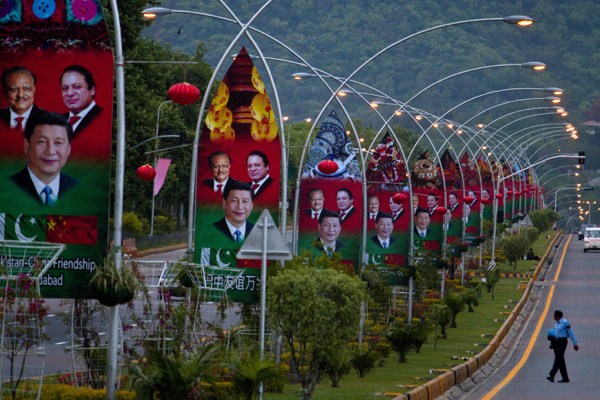 A Pakistani police officer walks pasts billboards showing pictures of Chinese President Xi Jinping, Pakistan’s President Mamnoon Hussain and Prime Minister Nawaz Sharif, Islamabad, Pakistan, April 19, 2015 (AP photo by Anjum Naveed).