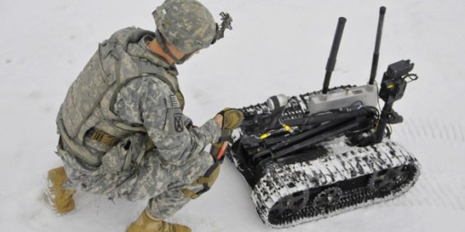 A soldier places simulated explosives in the hand of a Talon explosive ordinance disposal robot, Grafenwoehr Training Area, Germany, Feb. 20, 2013 (U.S. Army photo by Spc. Joshua Edwards).