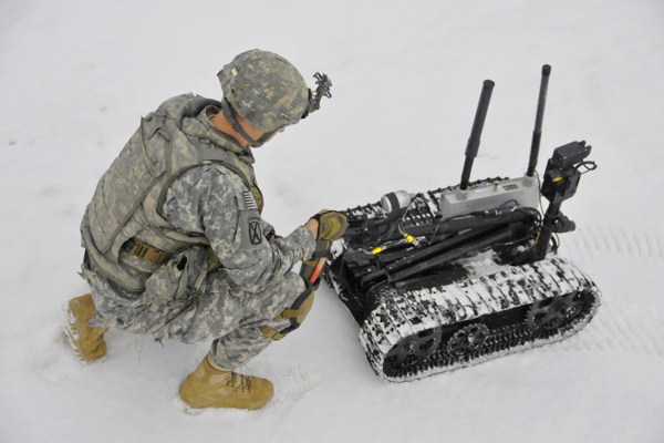 A soldier places simulated explosives in the hand of a Talon explosive ordinance disposal robot, Grafenwoehr Training Area, Germany, Feb. 20, 2013 (U.S. Army photo by Spc. Joshua Edwards).