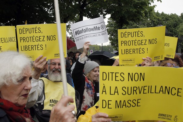Demonstrators hold placards reading “Say No to Mass Surveillance” and “Members of Parliament Protect our Freedom,” Paris, France, May 4, 2015 (AP photo by Francois Mori).