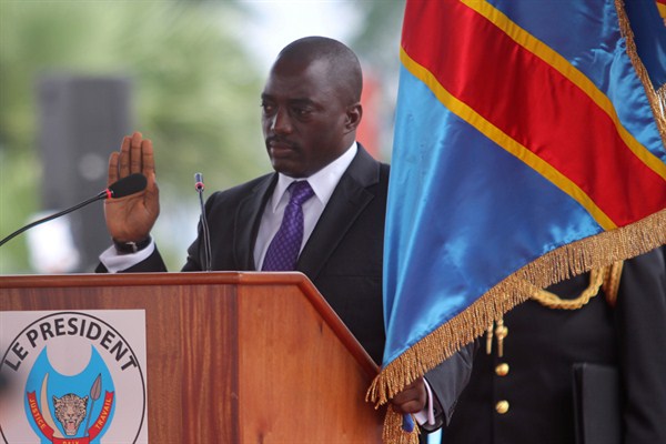Incumbent Congo President Joseph Kabila holds the Congolese flag as he takes the oath of office as he is sworn in for another term, Kinshasa, Congo, Dec. 20, 2011 (AP photo by John Bompengo).