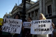 Women hold signs that read “Argentine justice stinks” and “Justice for Nisman” during a march for justice in the case of the mysterious death of late prosecutor Alberto Nisman, Buenos Aires, Argentina, Feb. 4, 2015 (AP photo by Rodrigo Abd).