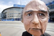 A protester wearing a mask depicting FIFA President Sepp Blatter stands in front of the building where the 65th FIFA congress takes place, Zurich, Switzerland, May 29, 2015 (AP photo by Michael Probst).