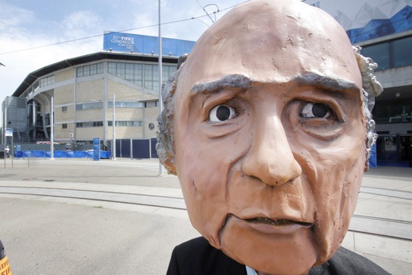 A protester wearing a mask depicting FIFA President Sepp Blatter stands in front of the building where the 65th FIFA congress takes place, Zurich, Switzerland, May 29, 2015 (AP photo by Michael Probst).