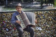 A man plays an accordion in front of the “lovelocks” left by tourists on the Pont des Artes, Paris, Sept. 6, 2013 (photo by Flickr user Ben Francis, licensed under Creative Commons Attribution 2.0 Generic).