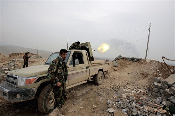 A Kurdish peshmerga fighter fires a weapon towards an Islamic State Group position, overlooking the town of Sinjar, northern Iraq, Jan. 29, 2015 (AP photo by Bram Janssen).