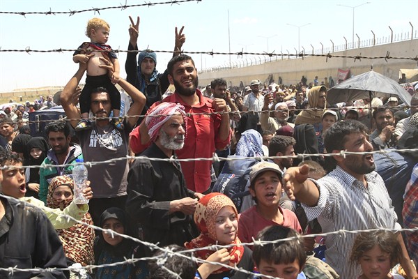 Syrian refugees mass at the Turkish border while they flee intense fighting in northern Syria between Kurdish fighters and Islamic State militants in Akcakale, southeastern Turkey, June 15, 2015 (AP photo by Lefteris Pitarakis).