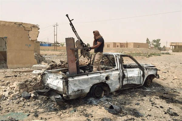 A militiaman allied with the Iraqi security forces dismantles a weapon from a destroyed vehicle belonging to the Islamic State group, southern Ramadi, Anbar province, Iraq, July 20, 2015 (AP Photo).