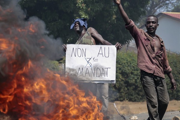 An opposition demonstrator holds a sign in French reading "No to a third term" next to a burning barricade, Bujumbura, Burundi, June 3, 2015 (AP photo by Gildas Ngingo).